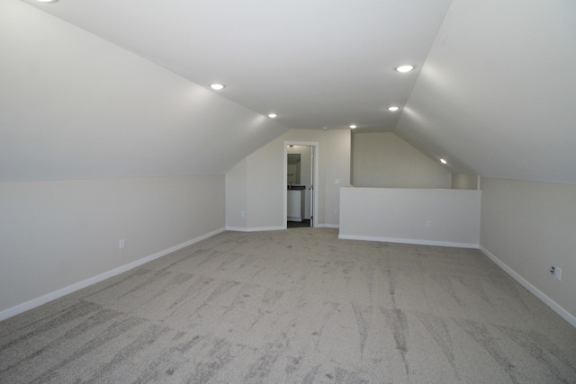 additional living space featuring lofted ceiling and light colored carpet