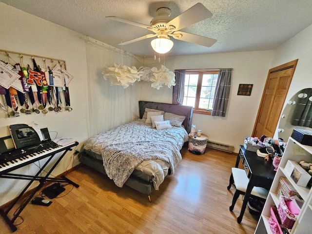 bedroom with a textured ceiling, a baseboard radiator, ceiling fan, and light hardwood / wood-style floors