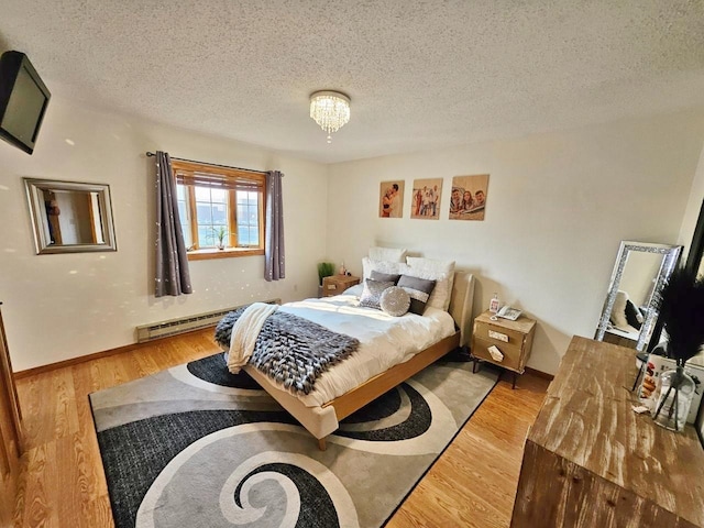 bedroom with hardwood / wood-style floors, a baseboard radiator, and a textured ceiling