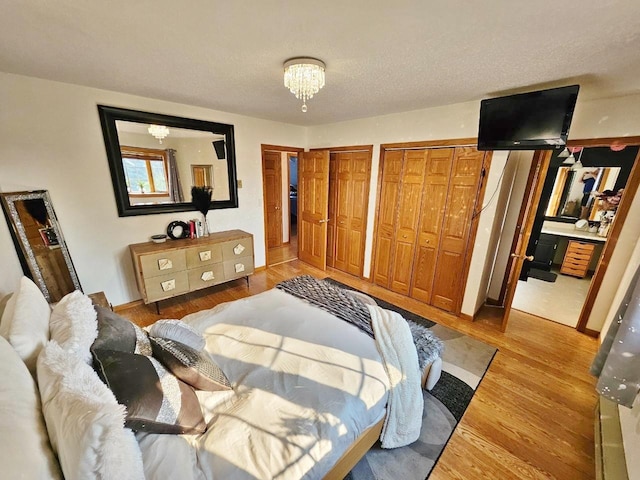 bedroom featuring a textured ceiling, multiple closets, and hardwood / wood-style flooring