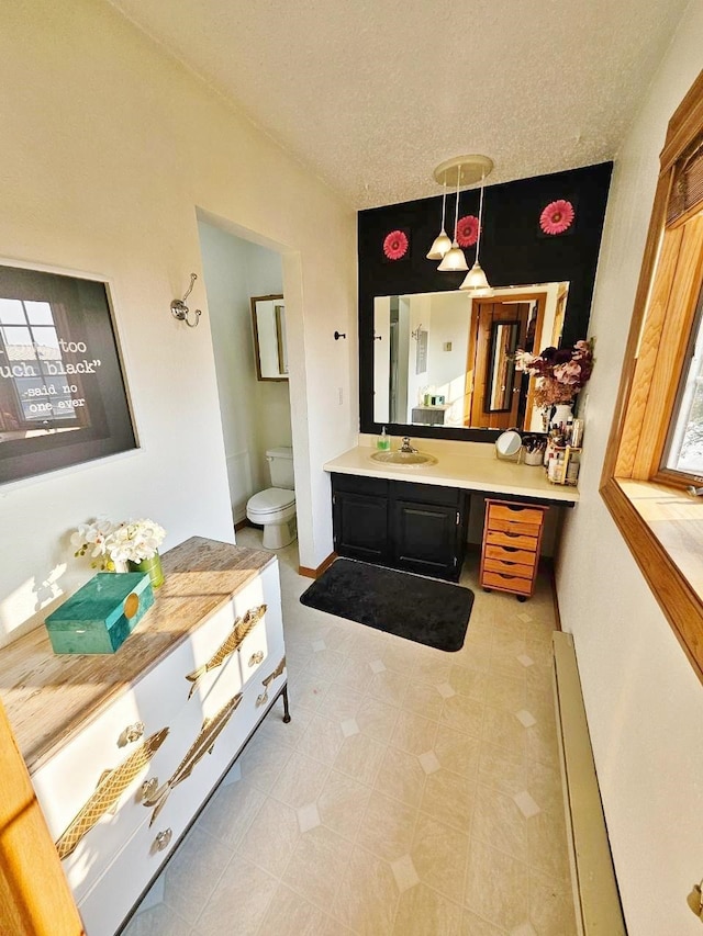 interior space featuring vanity, toilet, and a textured ceiling