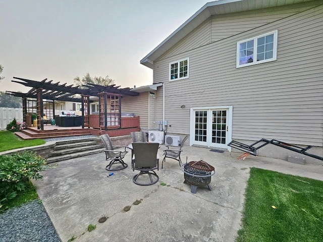 patio terrace at dusk featuring a fire pit, a deck, and a pergola