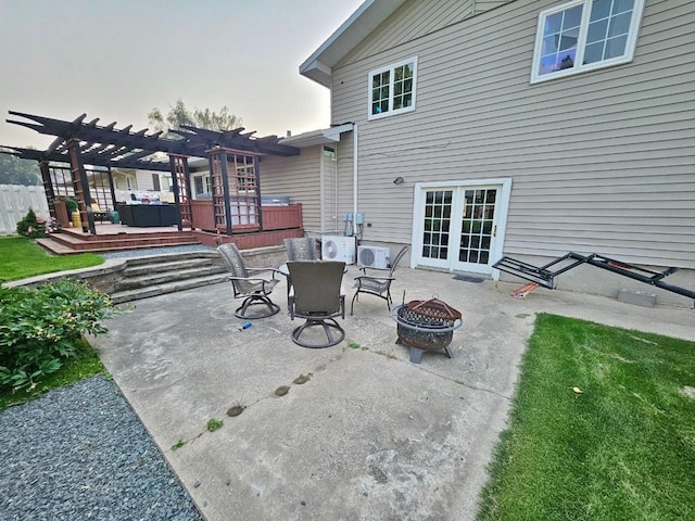 patio terrace at dusk with a pergola, a deck, and a fire pit