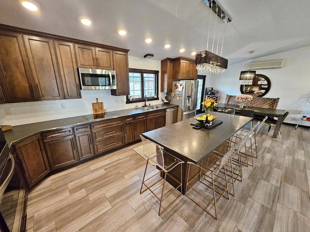 kitchen with a kitchen island, light hardwood / wood-style flooring, hanging light fixtures, stainless steel appliances, and sink