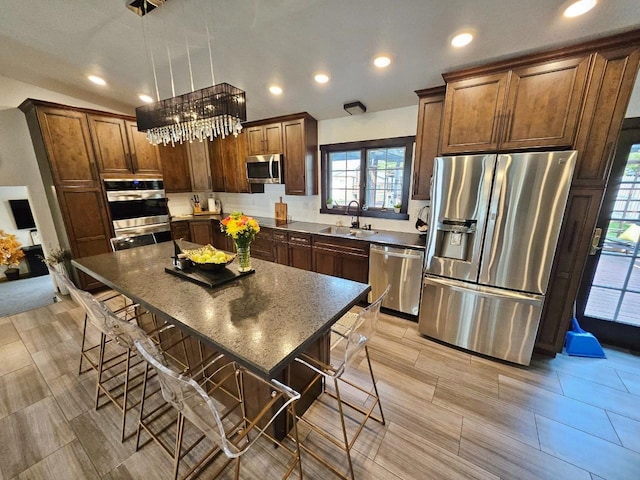 kitchen with decorative light fixtures, a center island, sink, appliances with stainless steel finishes, and a breakfast bar area