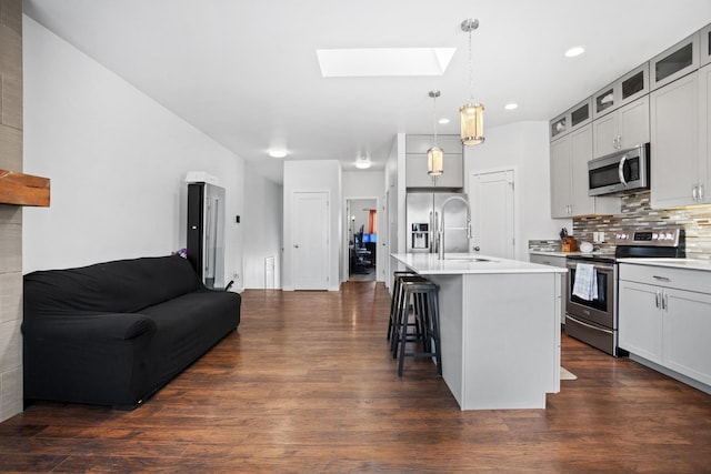 2424 Landmark Dr, Minot, ND 58703 - kitchen with a breakfast bar, a sink, stainless steel appliances, a skylight, and dark wood-style flooring