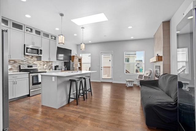 2424 Landmark Dr, Minot, ND 58703 - kitchen featuring backsplash, open floor plan, a kitchen breakfast bar, a skylight, and stainless steel appliances