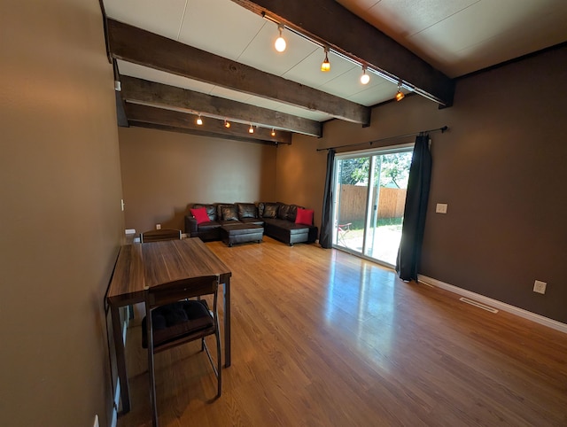 living room with track lighting, hardwood / wood-style flooring, and beam ceiling