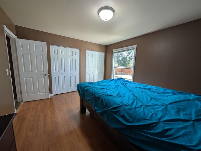 bedroom with multiple closets and hardwood / wood-style floors