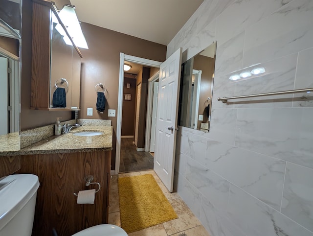 bathroom with tile walls, hardwood / wood-style flooring, vanity, and toilet