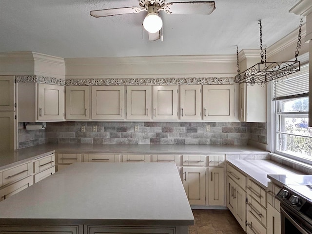 kitchen with ceiling fan, a center island, stainless steel range with electric cooktop, crown molding, and decorative backsplash