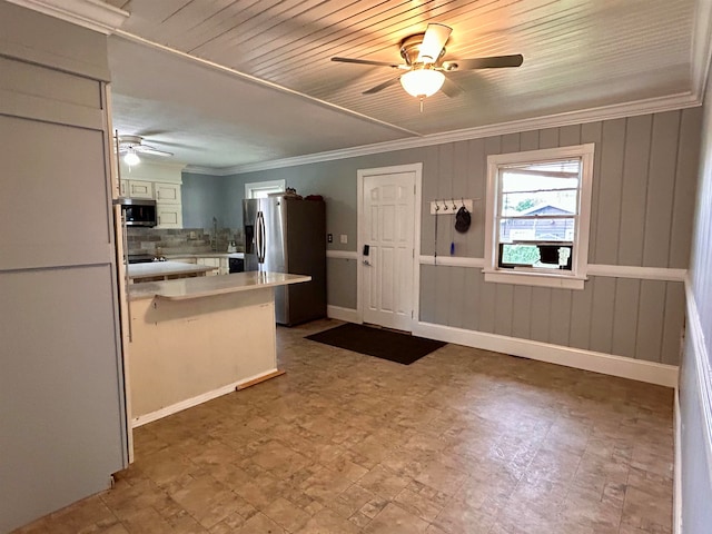 kitchen with appliances with stainless steel finishes, decorative backsplash, white cabinets, crown molding, and ceiling fan