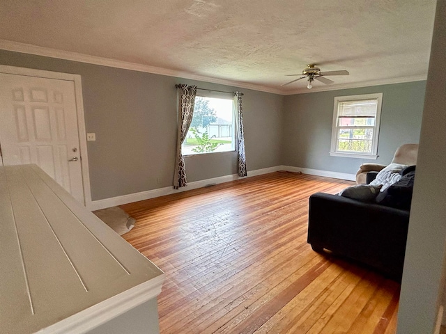 living room with light wood-type flooring, ceiling fan, plenty of natural light, and crown molding