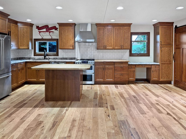 kitchen with sink, tasteful backsplash, wall chimney exhaust hood, stainless steel appliances, and light wood-type flooring