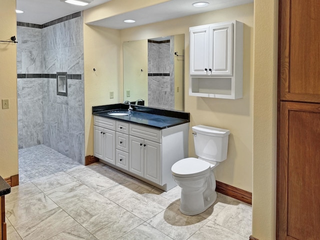 bathroom featuring a tile shower, vanity, and toilet