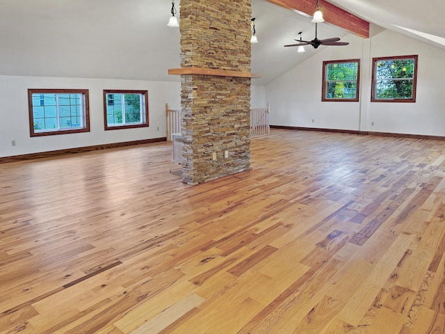 unfurnished living room with light wood-type flooring, vaulted ceiling with beams, a wealth of natural light, and ceiling fan