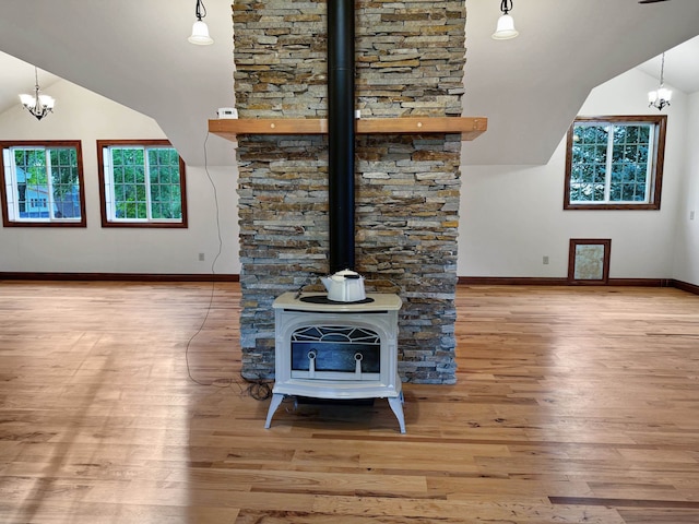 unfurnished living room with light hardwood / wood-style flooring, a wood stove, a chandelier, and high vaulted ceiling