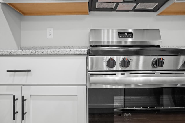 room details featuring white cabinets, light stone countertops, extractor fan, and stainless steel range oven