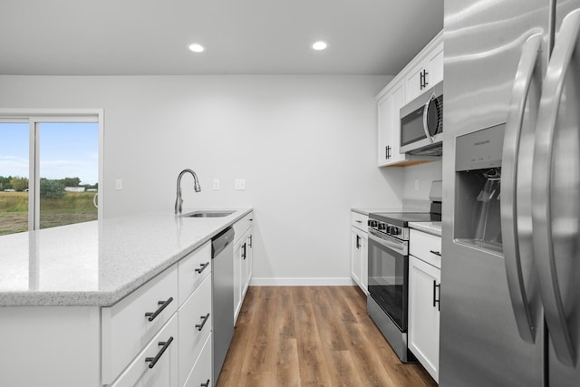 kitchen with stainless steel appliances, white cabinets, hardwood / wood-style floors, and sink