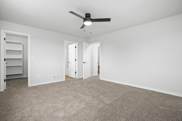 unfurnished bedroom with light carpet, a closet, ceiling fan, and a walk in closet