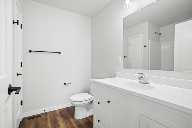 bathroom with wood-type flooring, vanity, walk in shower, and toilet