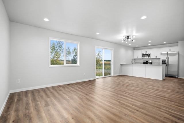 unfurnished living room featuring light wood-type flooring and sink