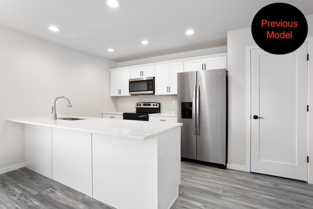 kitchen with light hardwood / wood-style floors, white cabinets, kitchen peninsula, stainless steel appliances, and sink