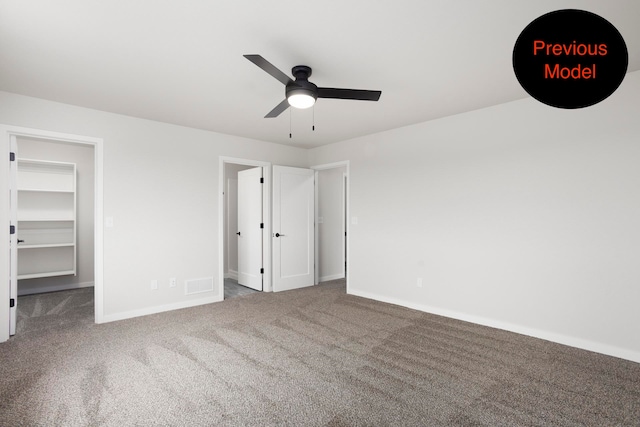 unfurnished bedroom featuring carpet floors, a spacious closet, ceiling fan, and a closet