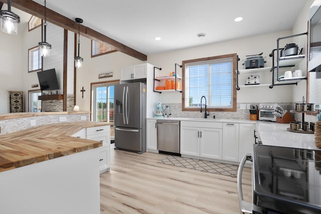 kitchen featuring pendant lighting, stainless steel appliances, white cabinets, and a wealth of natural light