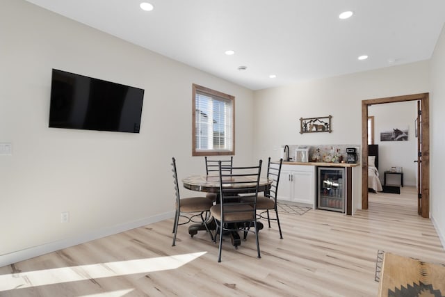 dining room featuring light hardwood / wood-style flooring, wine cooler, and wet bar