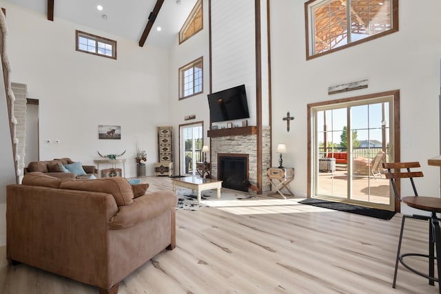 living room with a stone fireplace, light hardwood / wood-style flooring, beam ceiling, and high vaulted ceiling