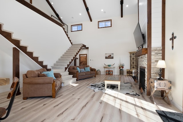 living room with high vaulted ceiling, beam ceiling, light hardwood / wood-style flooring, and a fireplace