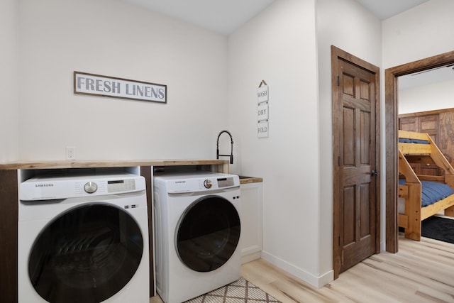 laundry area with light wood-type flooring, sink, and washer and dryer