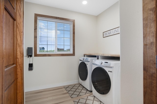 clothes washing area featuring light hardwood / wood-style floors and washer and dryer