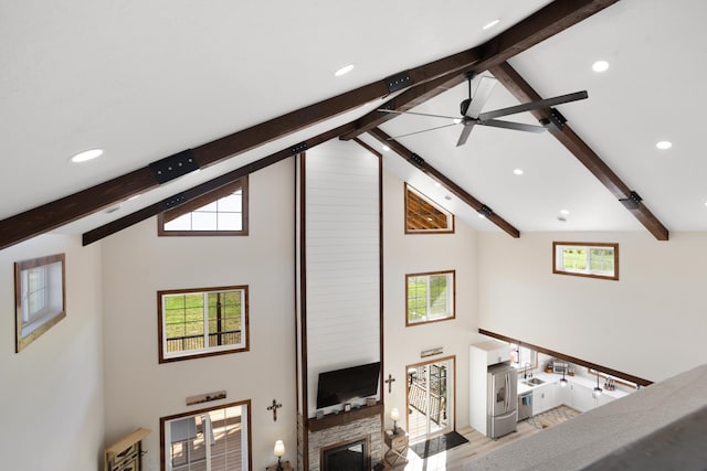 living room with ceiling fan, light hardwood / wood-style floors, beam ceiling, and high vaulted ceiling