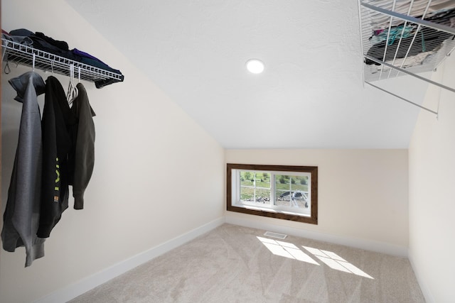 walk in closet featuring lofted ceiling and light colored carpet