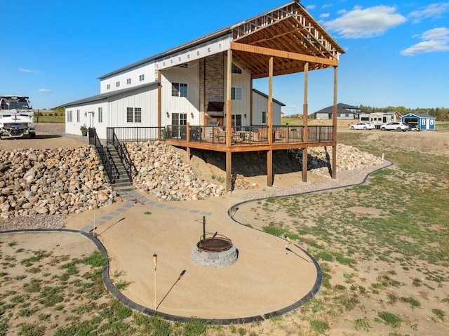 rear view of house featuring a wooden deck and an outdoor fire pit