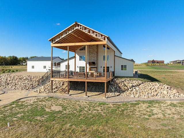 rear view of property featuring a wooden deck and a lawn