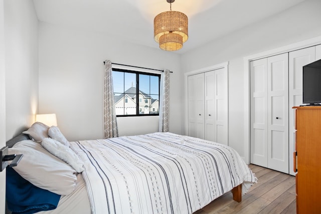 bedroom with multiple closets and light hardwood / wood-style flooring