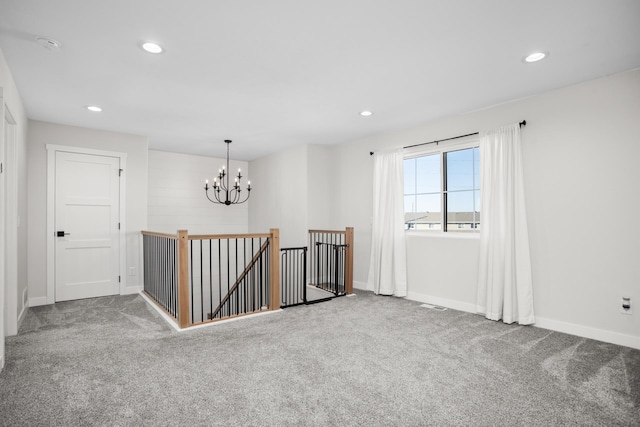 empty room with carpet floors and a notable chandelier