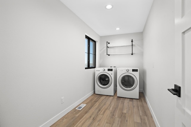 clothes washing area with light wood-type flooring and washing machine and clothes dryer