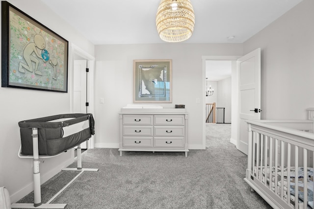 carpeted bedroom with a nursery area and a chandelier