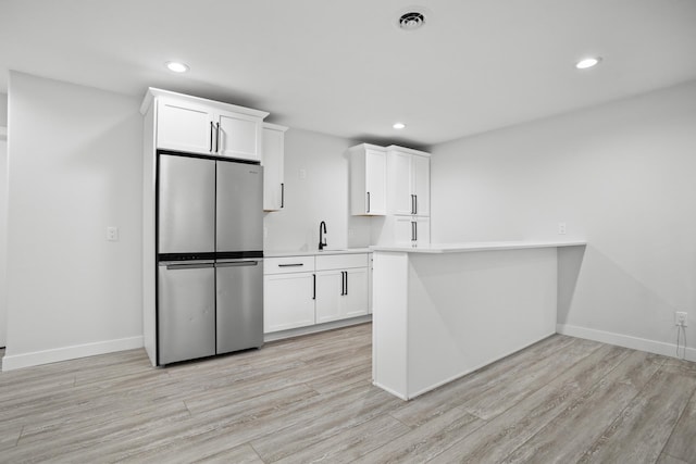 kitchen featuring light hardwood / wood-style flooring, white cabinetry, and stainless steel refrigerator