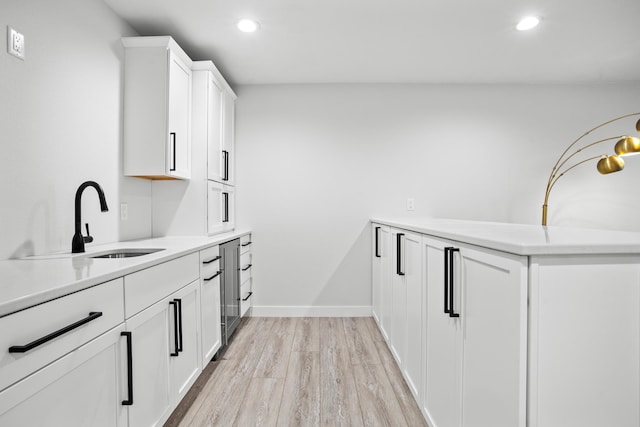 kitchen featuring white cabinets, light wood-type flooring, and sink