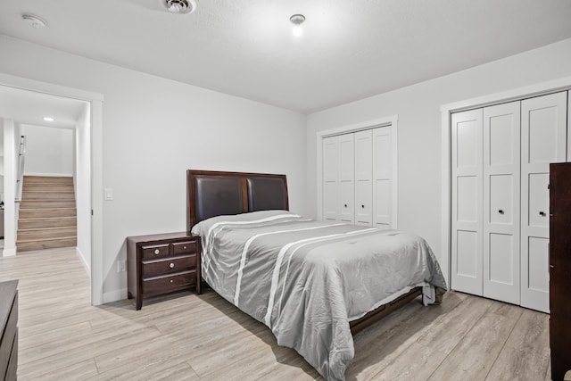 bedroom with light hardwood / wood-style floors and multiple closets