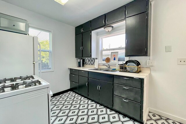 kitchen with a wealth of natural light, white appliances, light countertops, and a sink