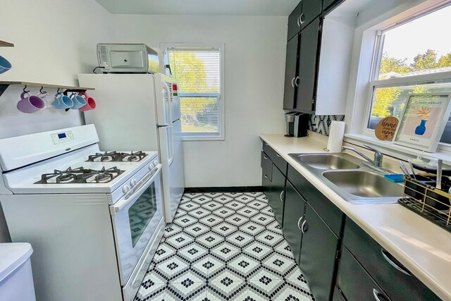 kitchen featuring a sink, gas range gas stove, dark cabinetry, and light countertops