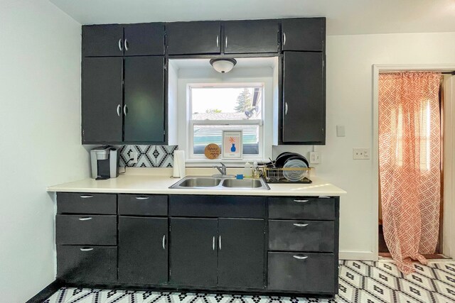 kitchen featuring light countertops, baseboards, and a sink