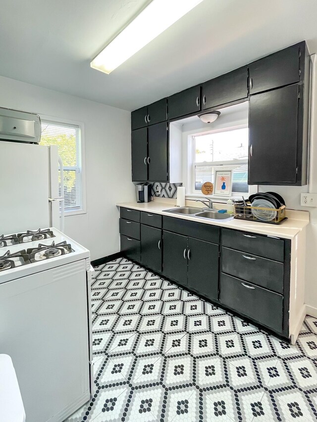 kitchen with white appliances, plenty of natural light, light countertops, and a sink