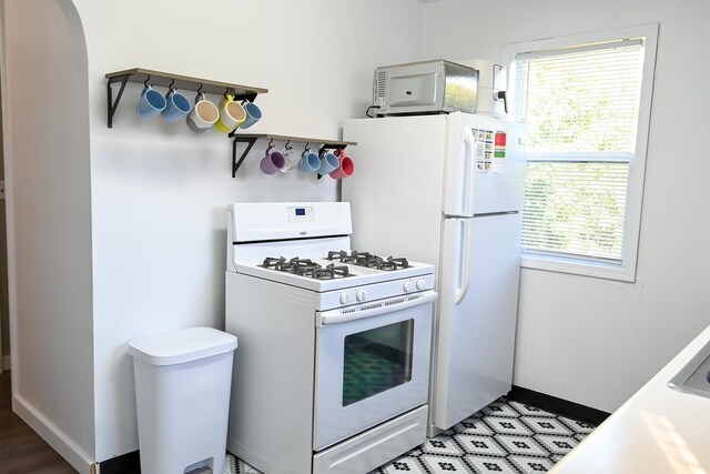 kitchen with white gas stove, a healthy amount of sunlight, arched walkways, and baseboards